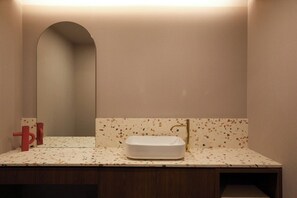 Un baño con un lavabo rectangular, un espejo y un toallero de pared.