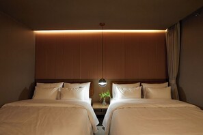 Una habitación de hotel con dos camas, una mesita de noche con un florero y un espejo en la pared.