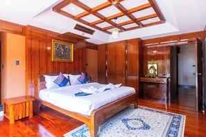 Un dormitorio amplio con una cama grande, paneles de madera, una mesita de noche pequeña y una mesita auxiliar.