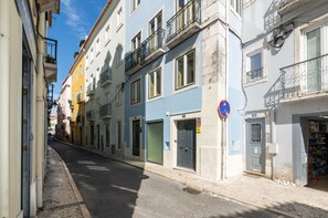 A narrow street lined with colorful buildings, a closed shop on the right, and a no parking sign. - Lbb1 (Lisbon)