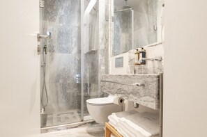 A modern bathroom with a glass-enclosed shower, a marble sink, and a toilet. - Lbb1 (Lisbon)