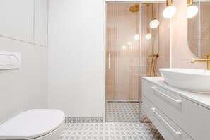A modern bathroom with a toilet, a sink with a gold faucet, and a shower with a glass door. - ShortStayPoland Jagiellońska Premium P6  (Warszawa)