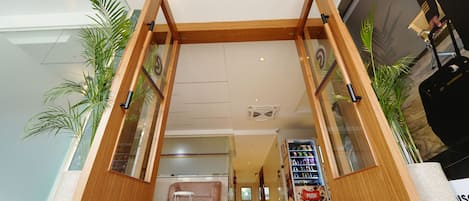 A hotel entrance with a wooden frame, glass panels, and potted plants.