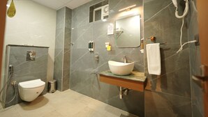 Ein modernes Badezimmer mit Marmorwand, Waschbecken in Weiß, Spiegel, Handtuchhalter und Fön.
