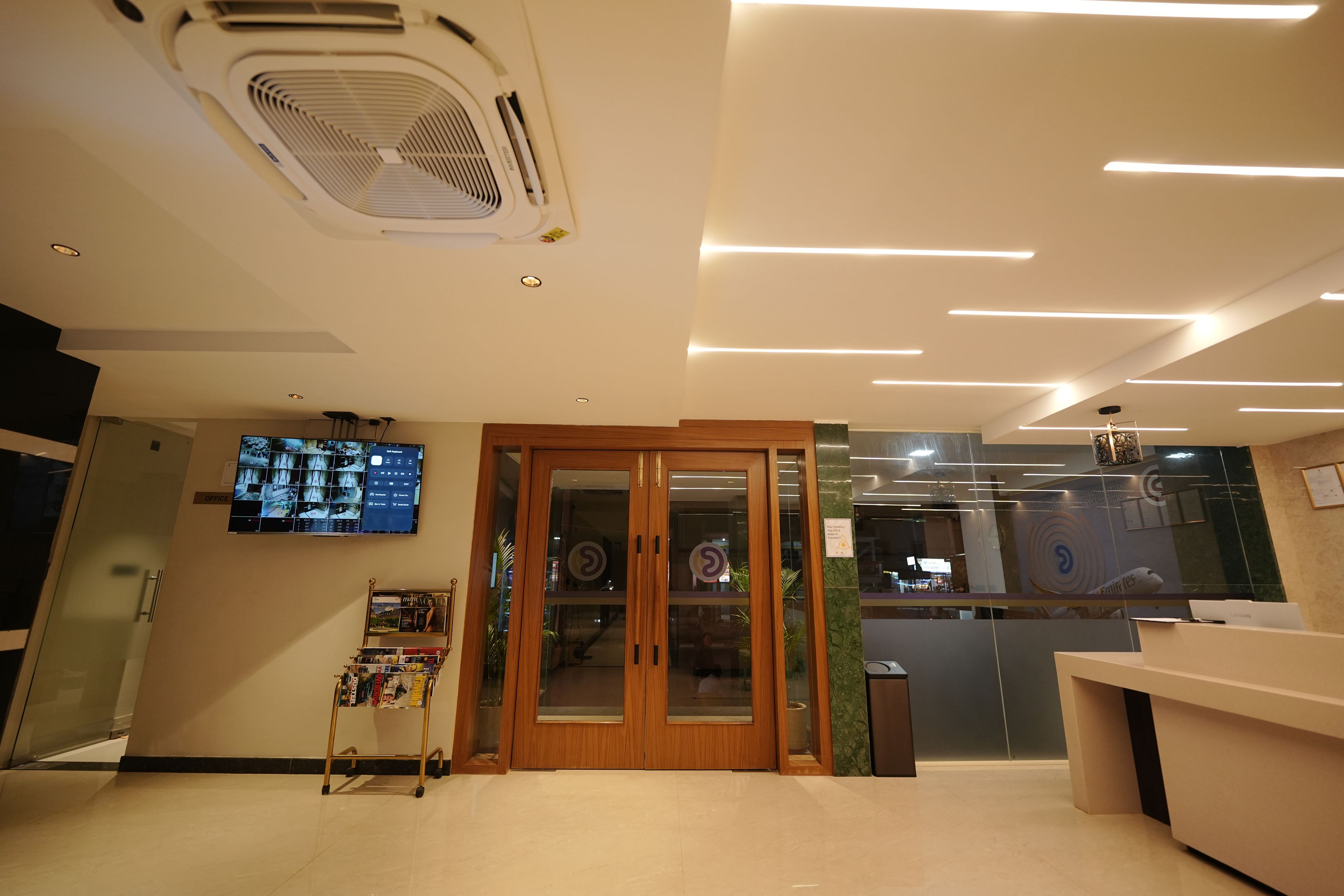 A reception area with a wooden door, a digital display, and a magazine rack.