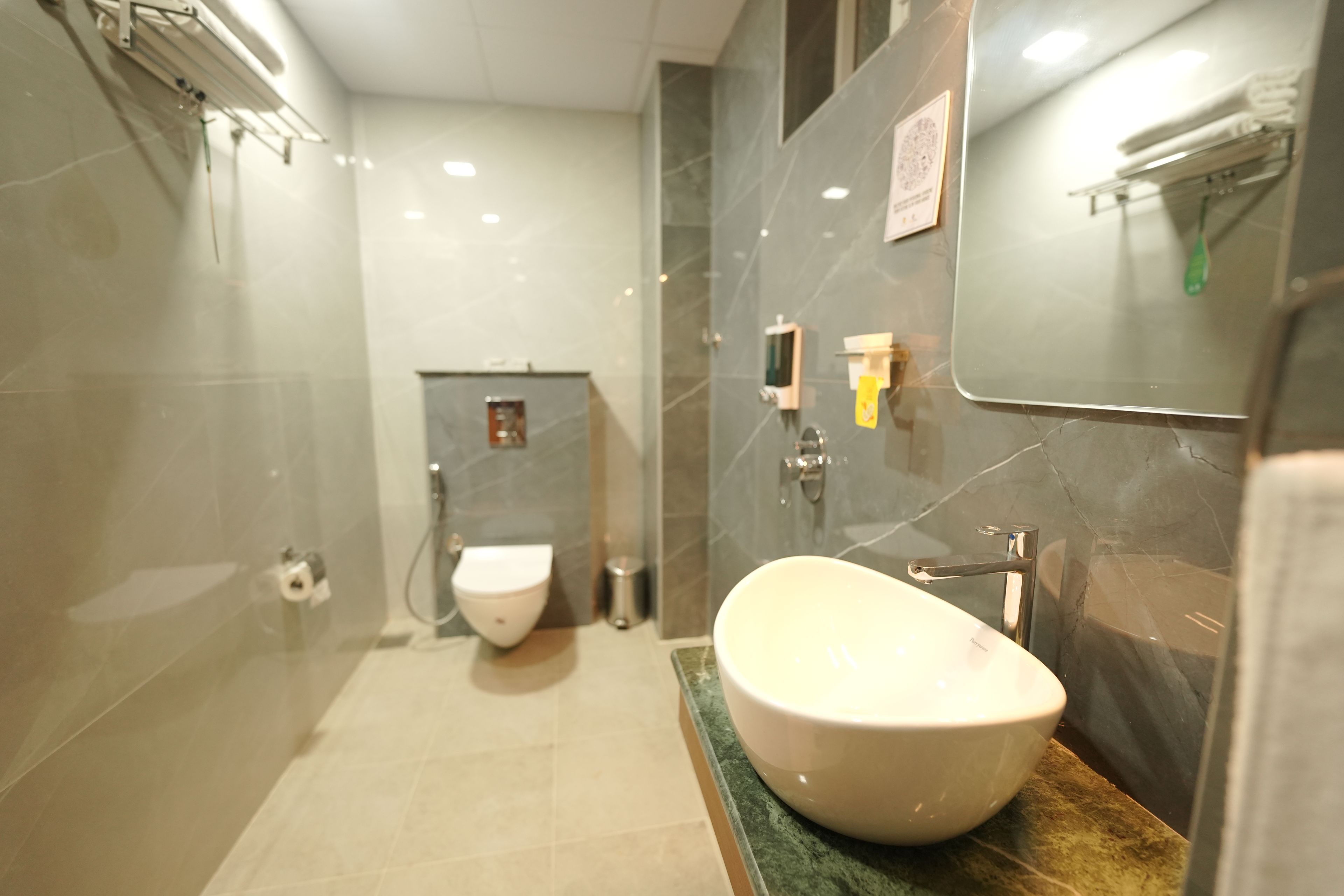 A modern bathroom with a large oval sink, a toilet, and a shower area.