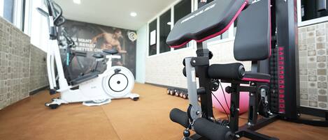 A gym with exercise equipment, a wall with a motivational poster, and a window with a view.