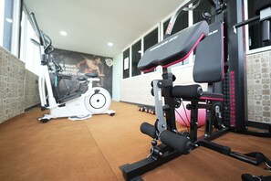 A gym with exercise equipment, a wall with a motivational poster, and a window with a view. - Galaxy Air Suites (Bengaluru)