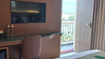 Une chambre d’hôtel comprenant un lit, un bureau avec une chaise, une télévision et une vue sur l’extérieur.