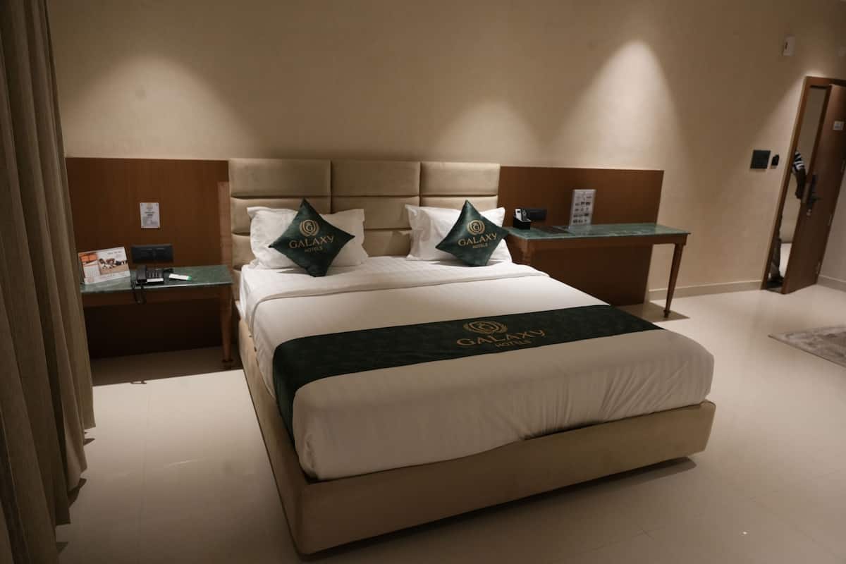 A hotel room with a large bed, two bedside tables, a nightstand, and a mirror.