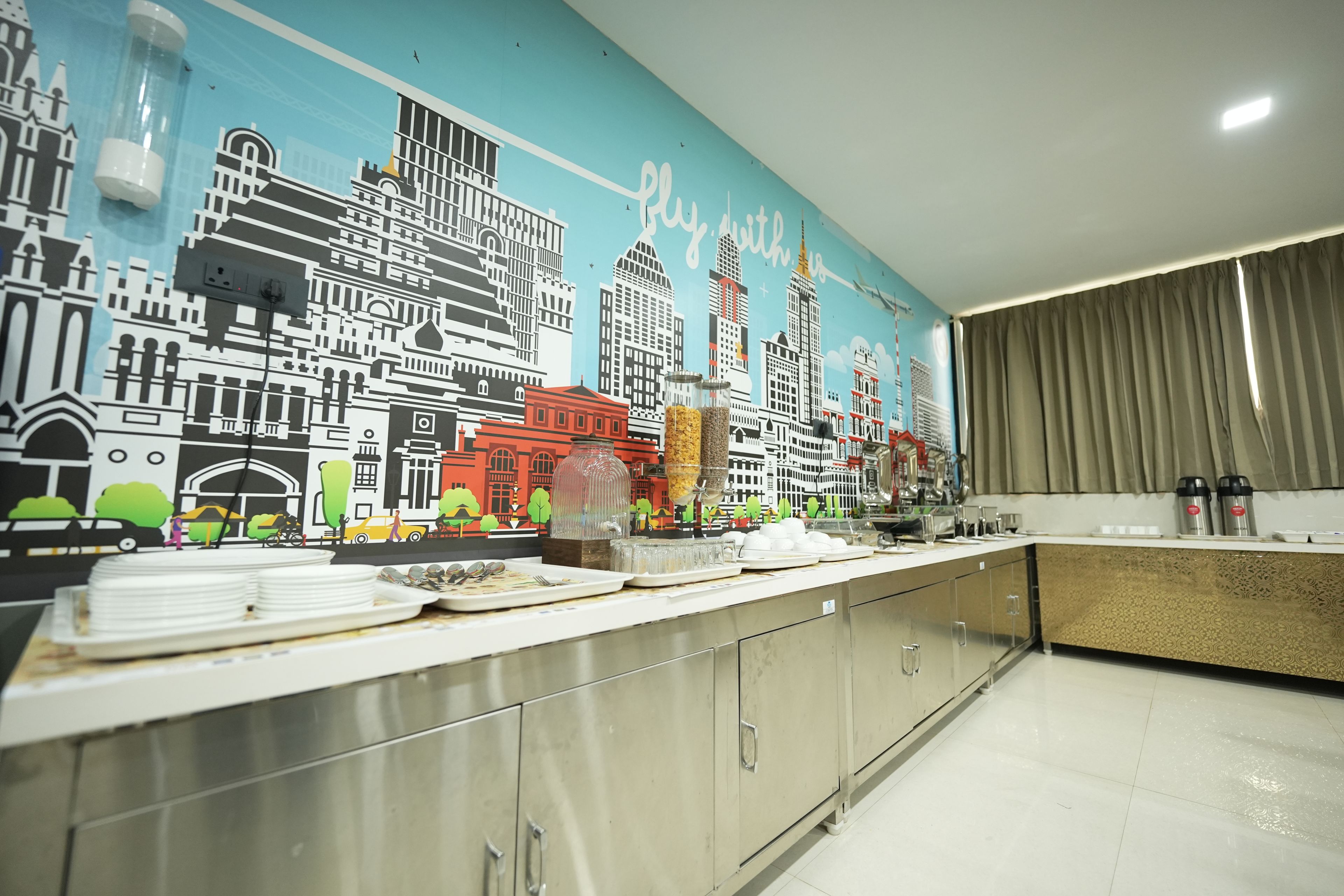 Une cuisine moderne agrémentée d’une fresque représentant un paysage urbain, d’appareils électroménagers en acier inoxydable et d’un buffet.
