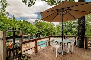 A wooden deck with a pool, outdoor seating, and a large umbrella. - Camper Cabin Escape with Fire Pit and Covered Porch in Branson, Missouri (Branson)