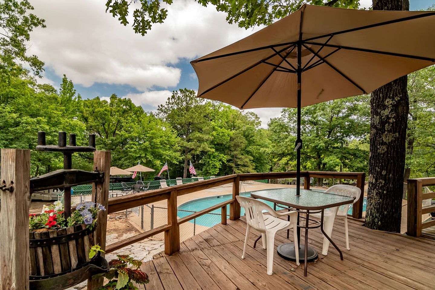 A wooden deck with a pool, outdoor seating, and a large umbrella.