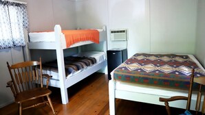Une chambre avec des lits superposés, une chaise, un bureau et un petit climatiseur.