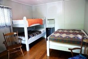A room with bunk beds, a chair, a desk, and a small air conditioning unit. - Camper Cabin Escape with Fire Pit and Covered Porch in Branson, Missouri (Branson)