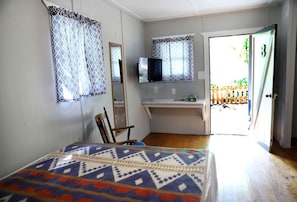 A bedroom with a bed, a chair, a desk, a TV, and a door leading outside. - Camper Cabin Escape with Fire Pit and Covered Porch in Branson, Missouri (Branson)