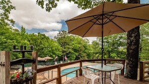 Une terrasse en bois avec une piscine, des sièges d’extérieur et un grand parasol.