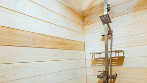 Une cabine de douche aux parois en bois, équipée d’un pommeau de douche, d’un pommeau de douche à main et d’une petite étagère.