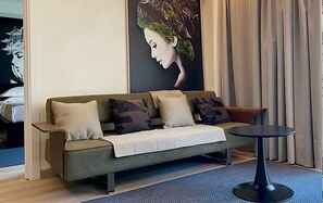Ein modernes Wohnzimmer mit einer Couch, Kissen, einem runden Tisch und einem großen Wandbild.