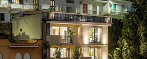 Un edificio residenziale a più piani con balconi, ampie finestre e un albero sullo sfondo.
