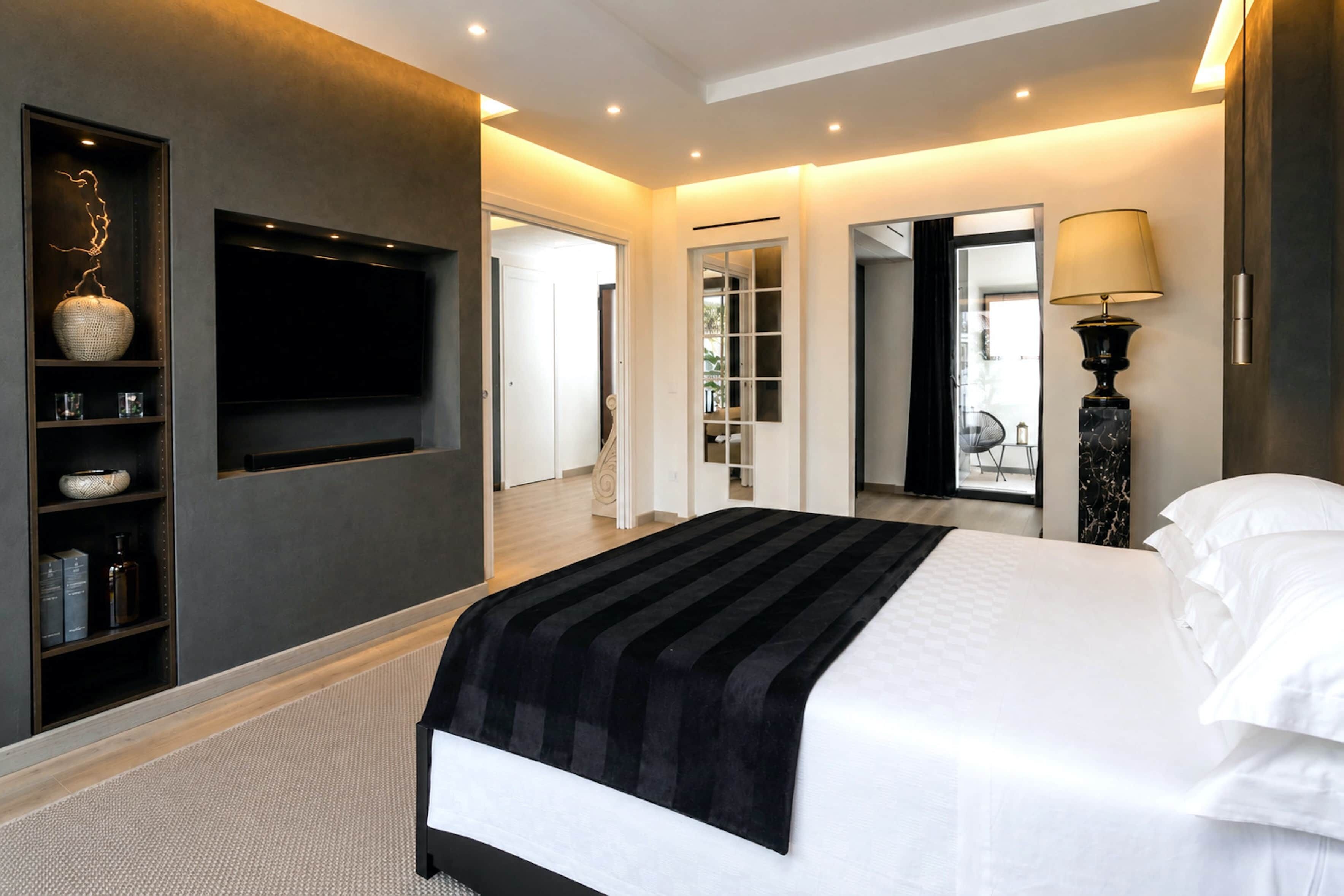 Une chambre d’hôtel moderne dotée d’un grand lit, d’un téléviseur à écran plat fixé au mur, d’une bibliothèque et d’un miroir.