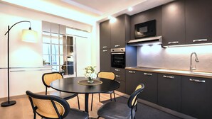 Una cocina moderna con muebles oscuros, un microondas integrado y un lavamanos de acero inoxidable.