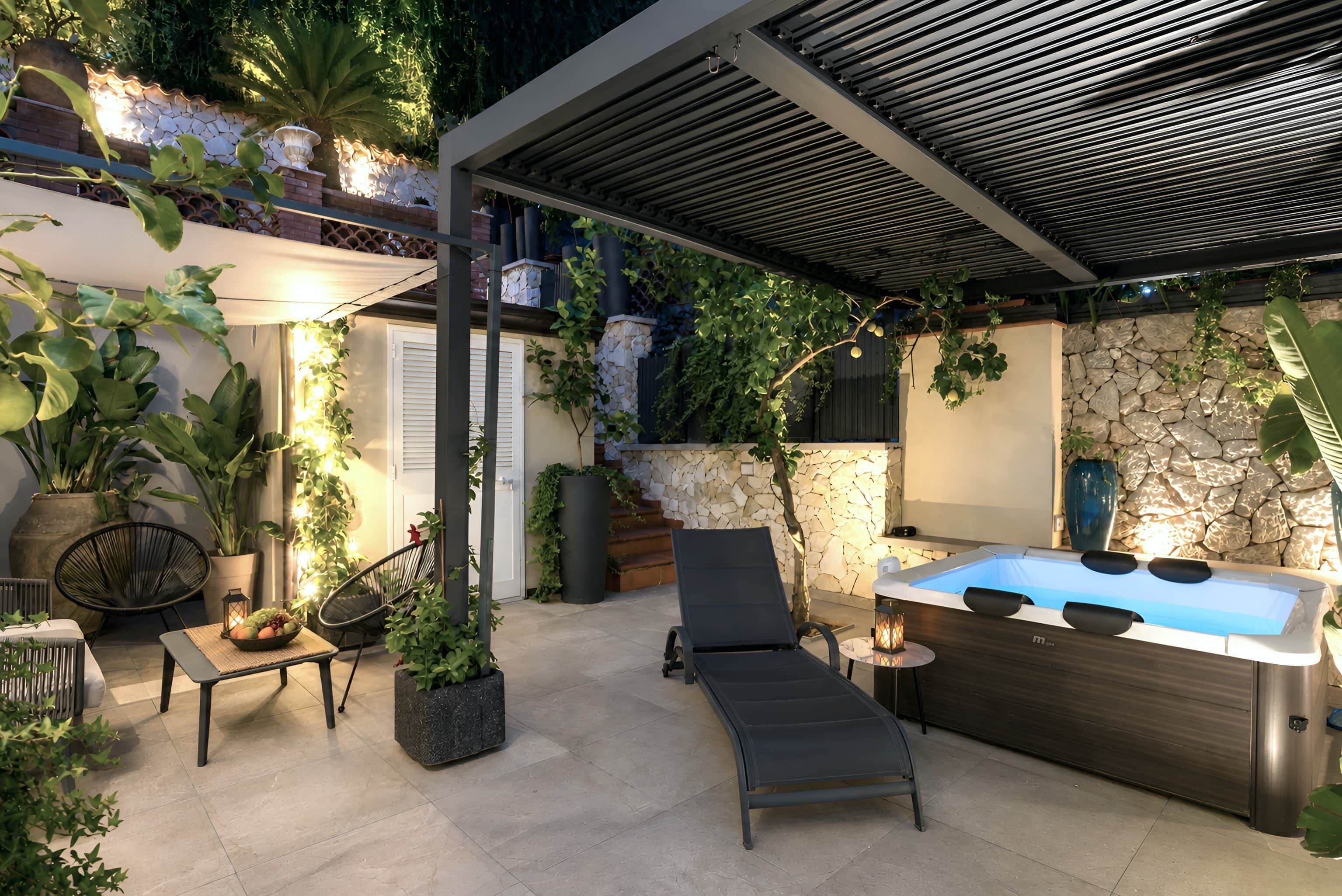 Eine Terrass mit Whirlpool, Liegestühlen und Kübelpflanzen.