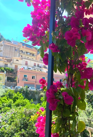 A balcony with pink flowers, a clear blue sky, and buildings in the background. - Alba Suite-Taormina In Light Suite (Taormina)