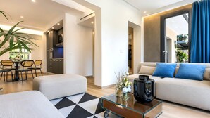 Una sala moderna con un sofá, un reposapiés, una mesa de centro y un comedor con sillas y una mesa.