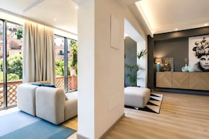 A modern living room with a sofa, a dining area with a table, and a view of the outside. - Alba Suite-Taormina In Light Suites (Taormina)