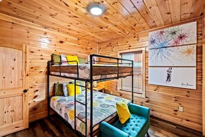 A bunk bed room with wooden walls, a ceiling light, and a framed artwork. - Family Cabin with Indoor Pool, Hot-Tub and Pool Table in Tennessee (Pigeon Forge)