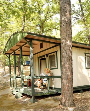 A small cabin with a porch, a single window, and a door. - Rustic Camper Retreat with Fire Pit & Rocking Chairs in Branson, Missouri (Branson)