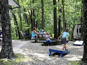 Ein Freizeitareal im Freien mit Picknicktischen, einer Wippe und einem überdachten Sitzbereich.