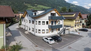 A multi-story hotel with a parking area, surrounded by mountains. - Haus3310 by we rent (Bad Hofgastein)