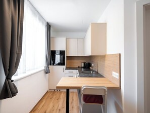 Una kitchenette compacta con horno integrado, cafetera y lavamanos.