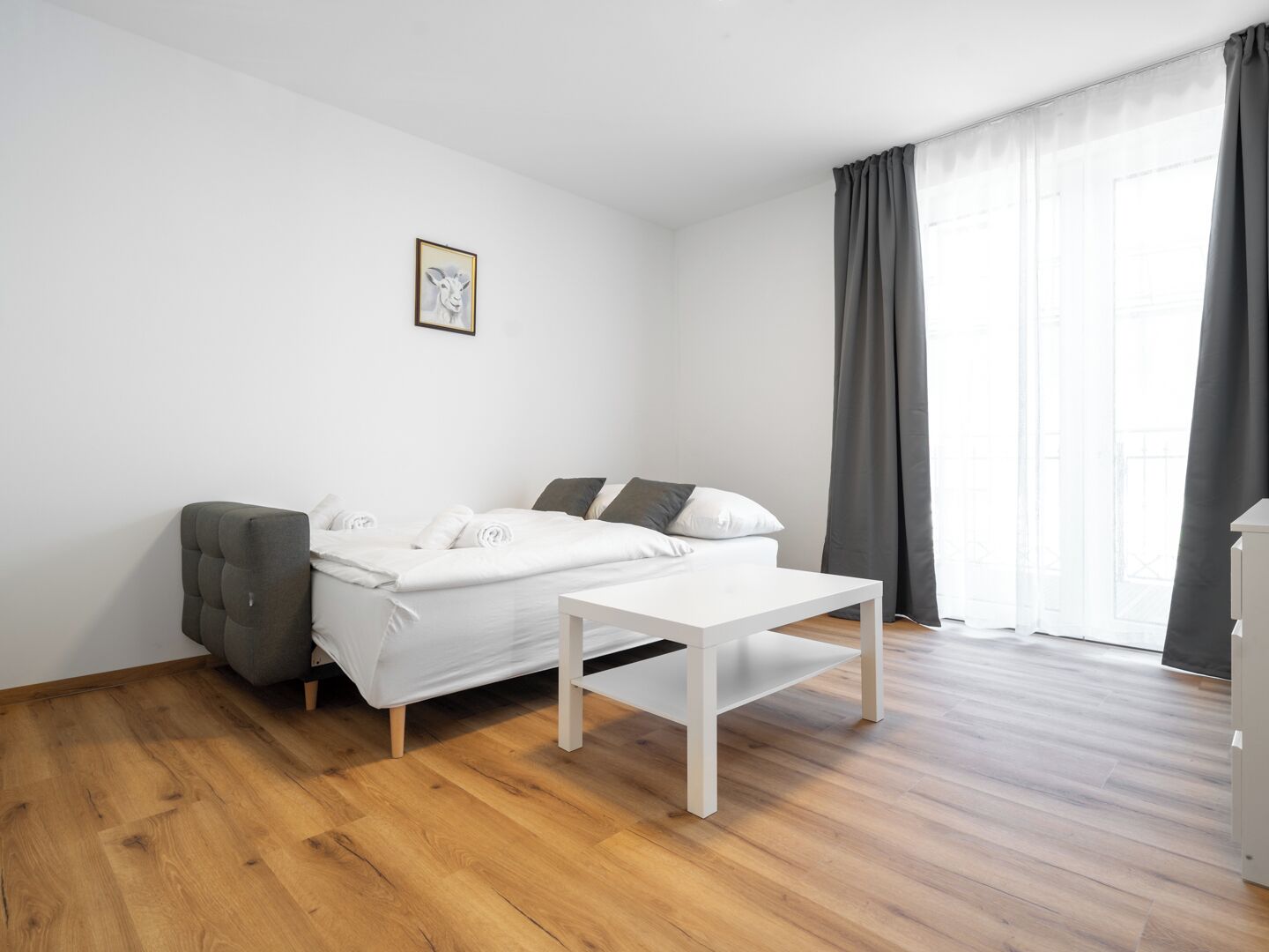 Un dormitorio minimalista con una cama, una mesita y una silla.