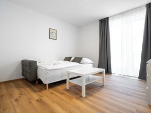Un dormitorio minimalista con una cama, una mesita y una silla.