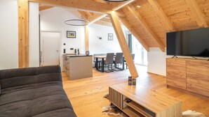 A modern interior with a wooden ceiling, a sofa, a TV, and a dining area. - Haus3310 by we rent (Bad Hofgastein)