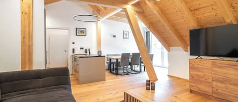 A modern interior with a wooden ceiling, a sofa, a TV, and a dining area.
