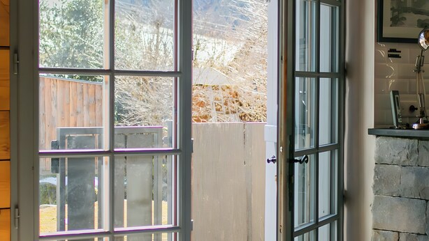 A room with a large window, a door, and a stone wall.