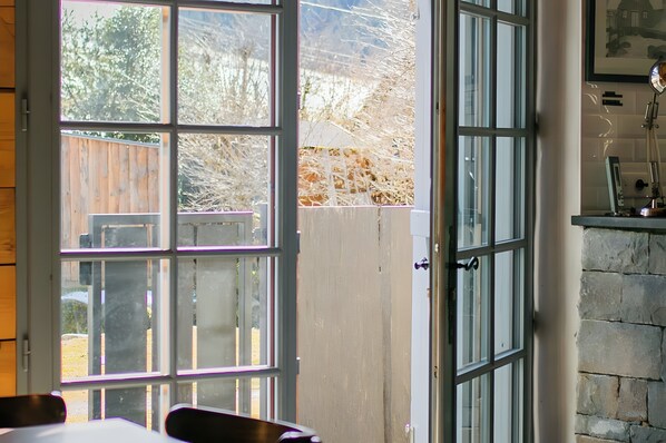 A room with a large window, a door, and a stone wall.