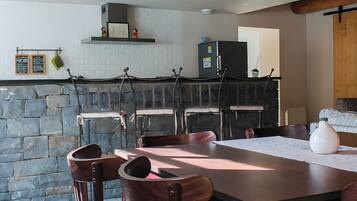 A stone wall, wooden chairs, a table, a refrigerator, and a hanging menu.