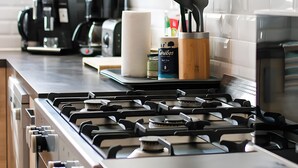 A kitchen with a gas stove, coffee maker, and various kitchen utensils.