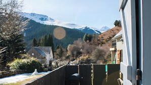 A residential area with a house, a barbecue grill, and a mountain backdrop.
