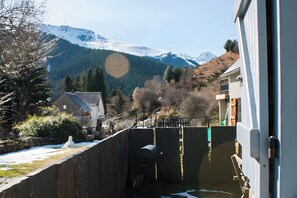 A residential area with a house, a barbecue grill, and a mountain backdrop.