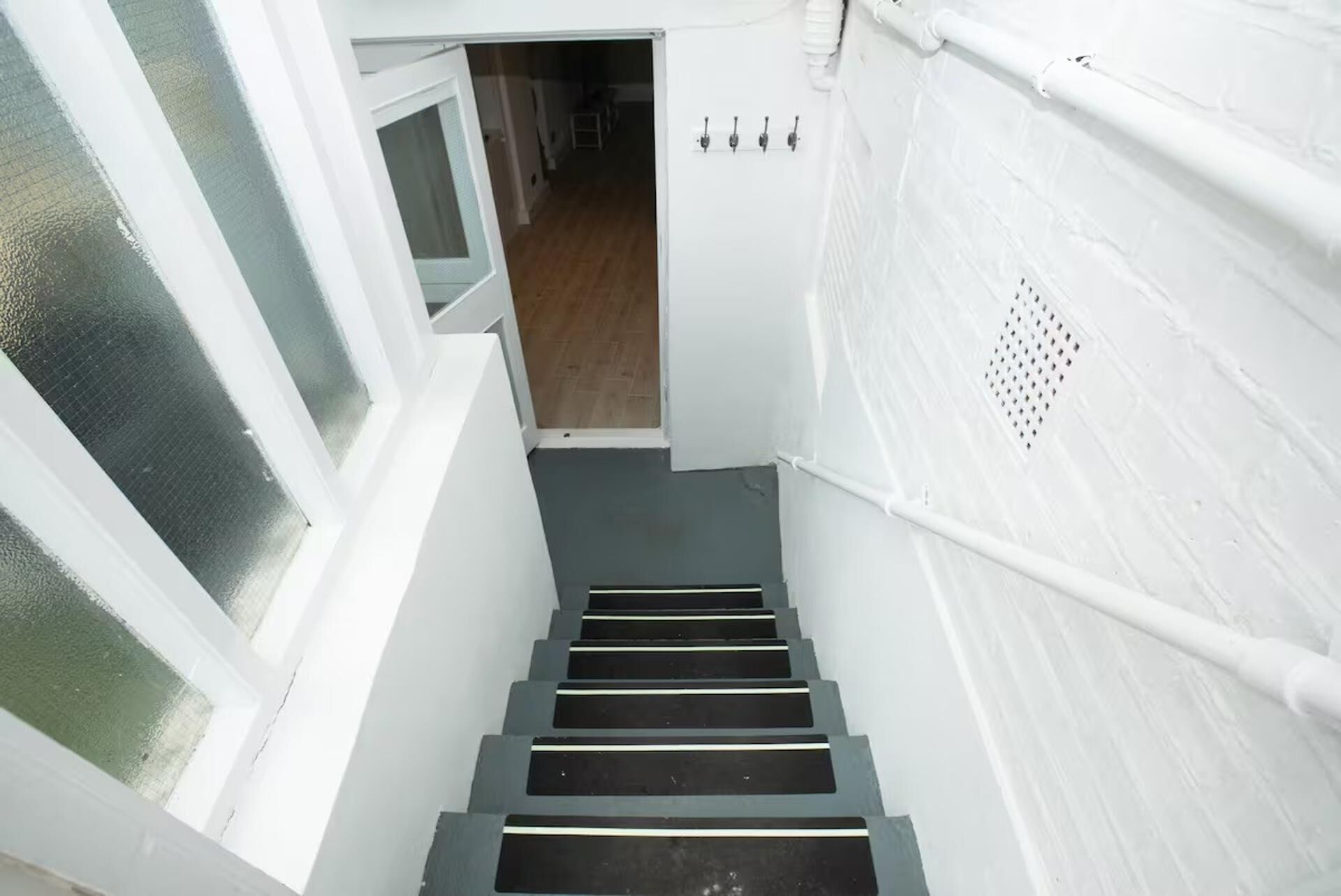 A staircase with white walls and a wooden floor leading to a room.