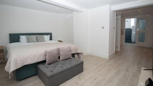 A bedroom with a bed, a bench, and a staircase. - Basement Flat Sleeps 3 With Patio (London)