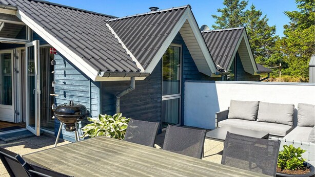 Eine Terrasse mit Tisch, Stühlen, einem Grill und einer Couch.