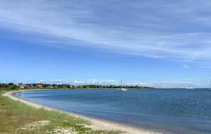 A coastal landscape with a clear sky, a sandy beach, and a distant view of a town with buildings and a bridge. - Awesome apartment in Fur with house sea view (Fur)