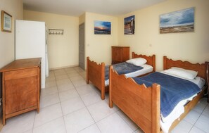 Ein Zimmer mit zwei Holzbetten, einem Holzschrank, einem weißen Kleiderschrank und einer Tür.